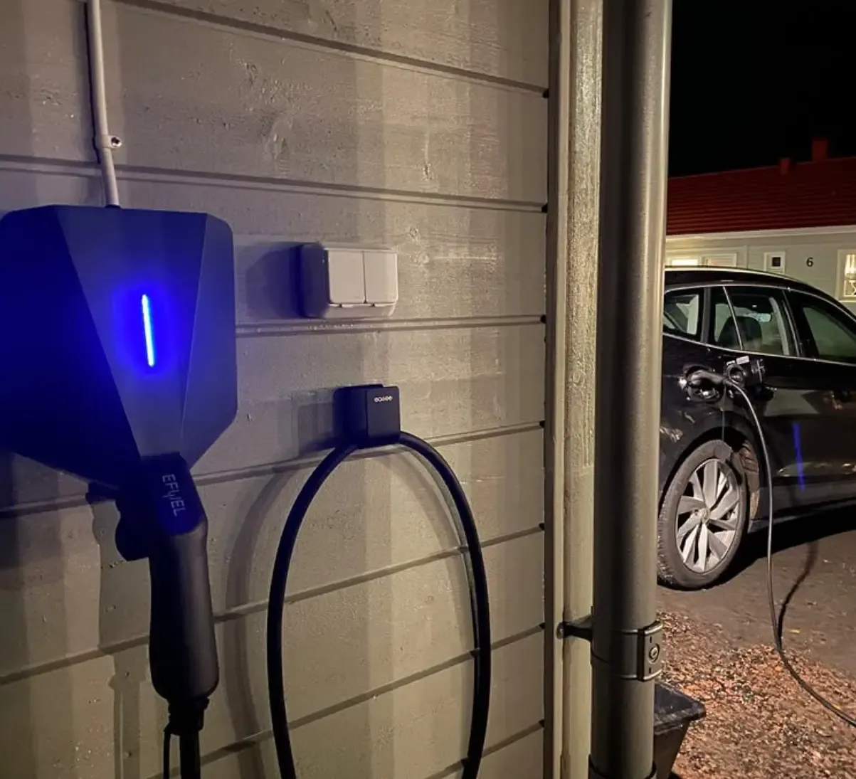 Laddbox monterad i ett garage med en elbil ansluten till laddkabeln