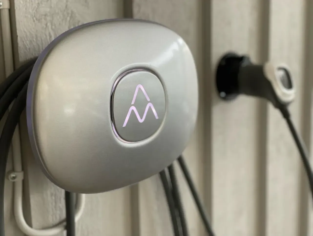Närbild av en väggmonterad laddbox med ansluten laddkabel