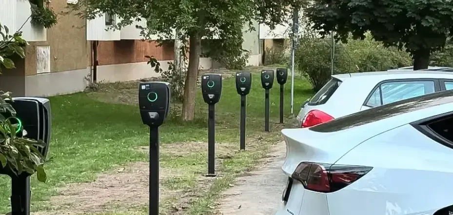 Rad med laddstolpar längs en parkering med anslutna elbilar